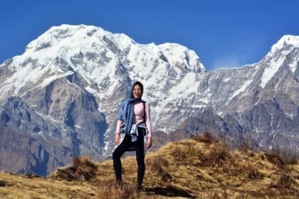 A beautiful lady stands gracefully in front of the majestic Annapurna mountain range, embracing the breathtaking Himalayan scenery.