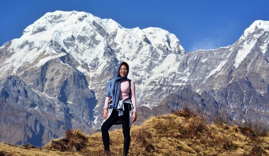 A beautiful lady stands gracefully in front of the majestic Annapurna mountain range, embracing the breathtaking Himalayan scenery.