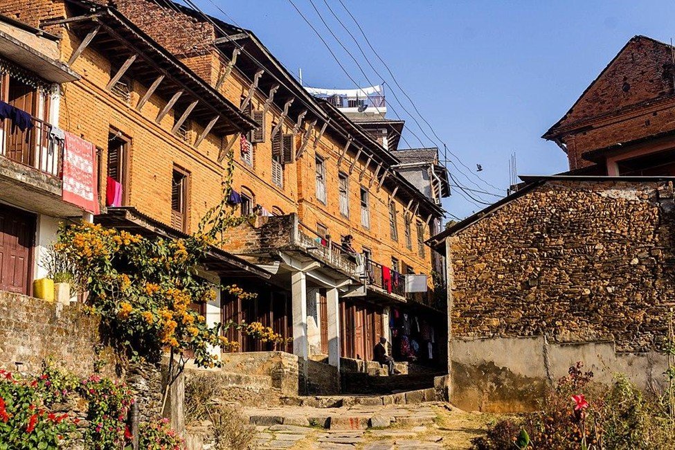 Charming stone-paved street in Bandipur with traditional Newari buildings and hills in the background.